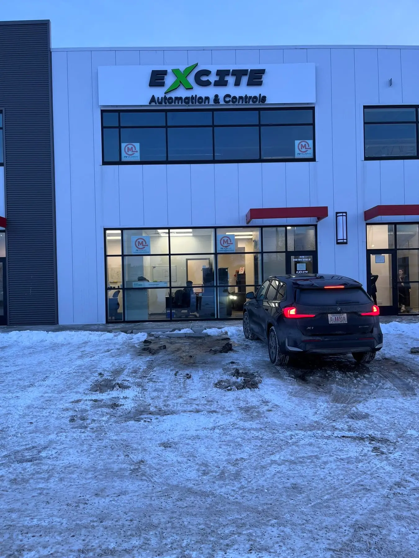 An illuminated company sign mounted on the front of a Calgary automation and controls facility