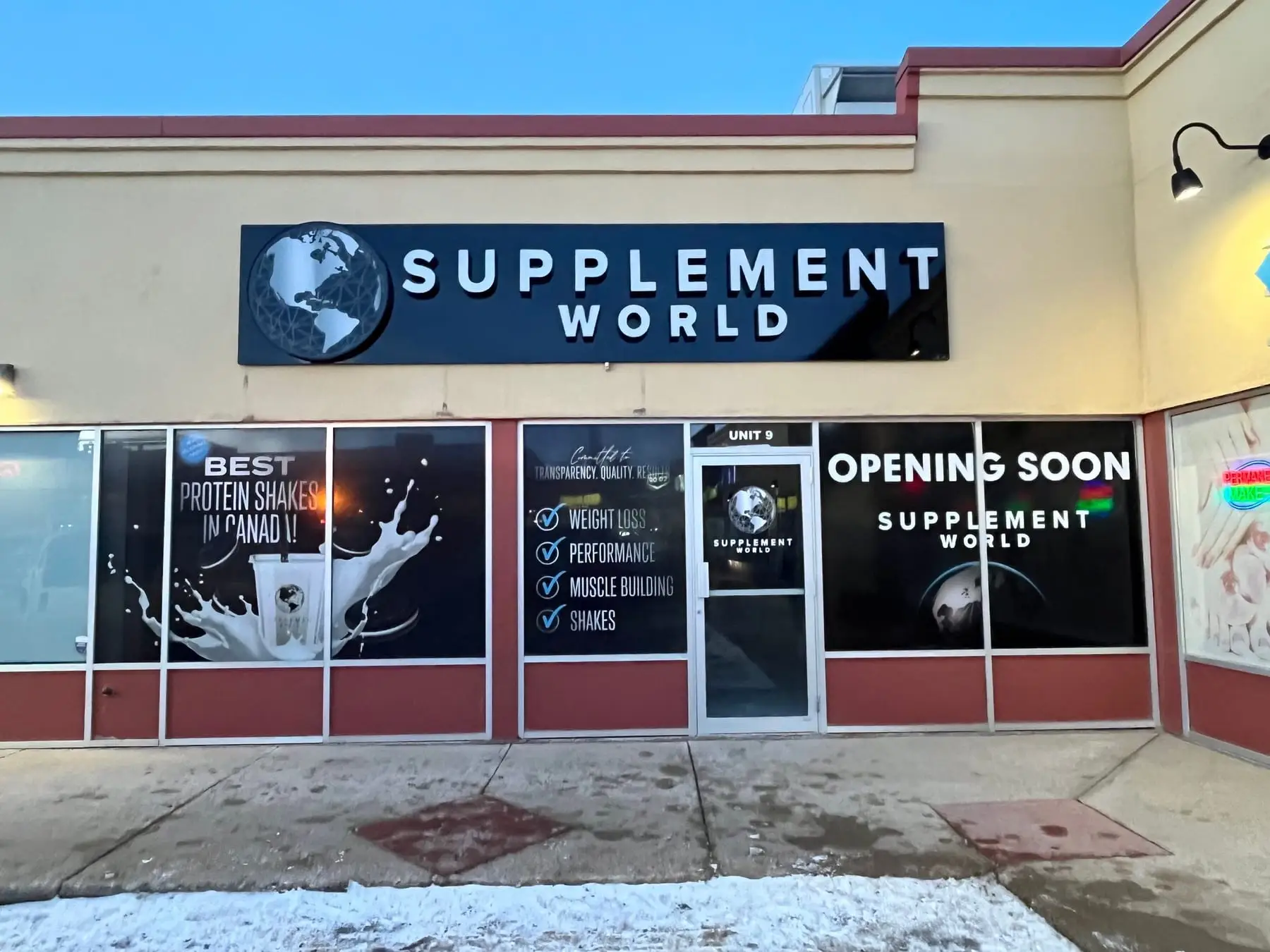 An illuminated sign cabinet mounted above a Calgary retail unit, with printed window graphics below it