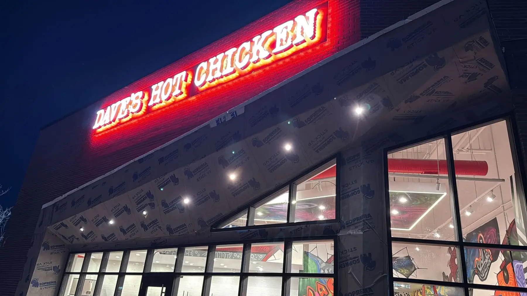 Illuminated red channel letters glowing above a restaurant entrance at night in Calgary