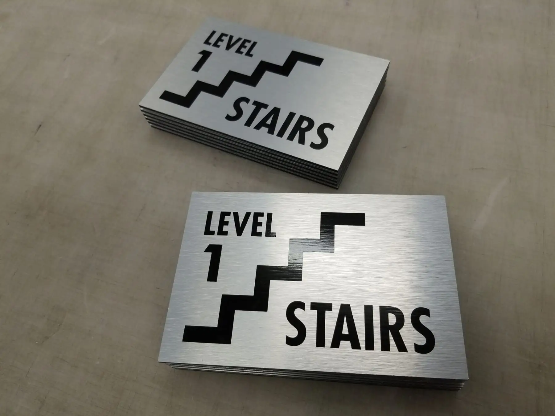 Brushed metal stairwell level identification plaques laid out after fabrication